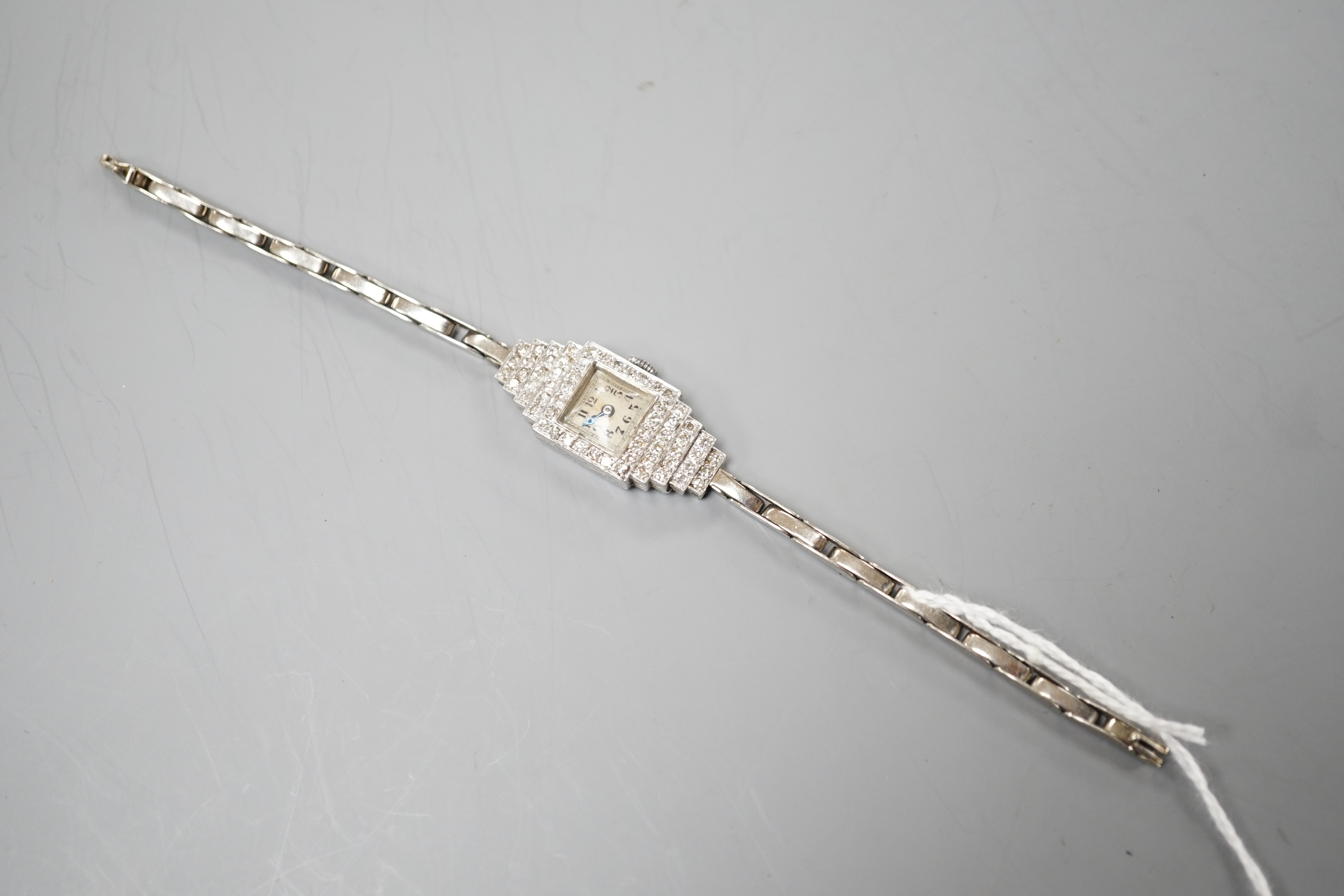 A lady's mid 20th century white metal (stamped platinum) and diamond cluster set Vertex cocktail watch, with stepped lugs, on a 9ct white metal expanding bracelet, 15.5cm, gross weight 15.6 grams.